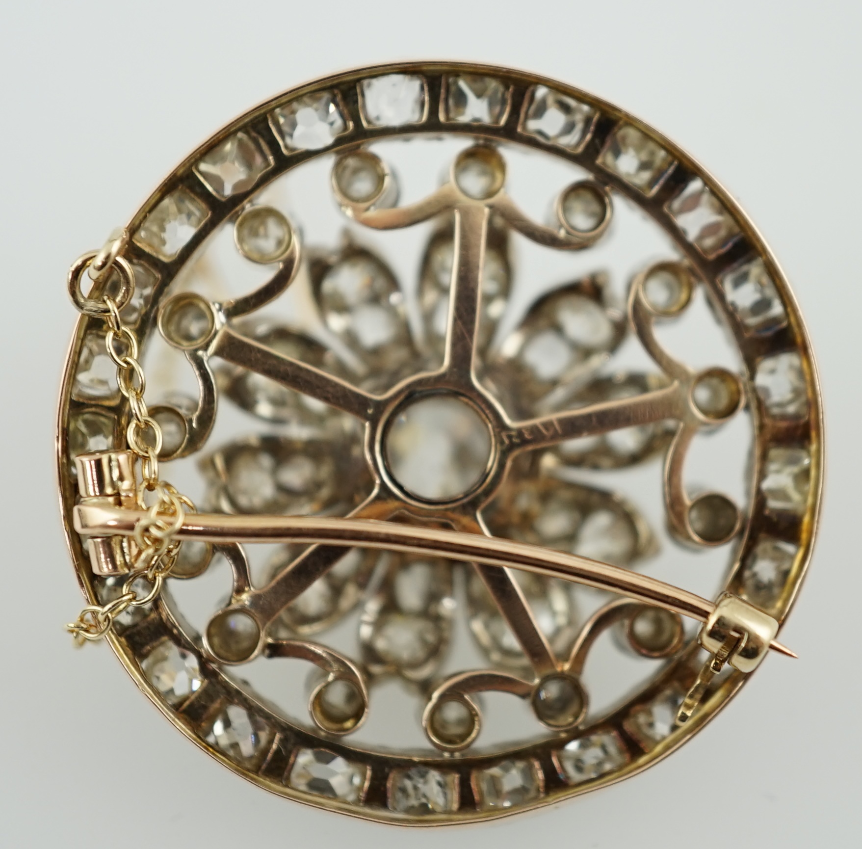 An Edwardian pierced gold and diamond cluster set circular brooch, with central cushion cut stone, diameter 34mm, gross weight 14.4 grams. Condition - fair to good